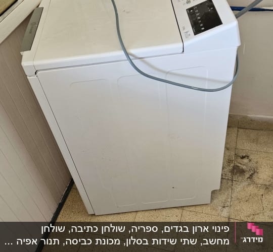מכונת כביסה לבנה עם צינור מים על רצפה מלוכלכת